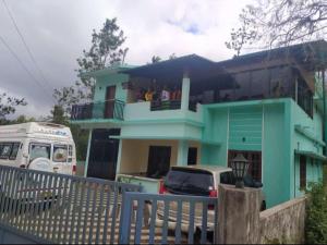 une maison bleue avec une camionnette garée devant elle dans l'établissement Wayanad Snow Vibes, à Vythiri