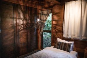 a bedroom with a bed and a window and a chandelier at LOGIN OKINAWA -soil- in Onna