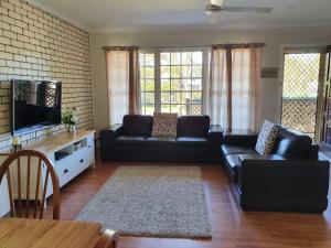 un salon avec un canapé et une télévision dans l'établissement Cuddles Cottage holiday house near Dutchies, à Nelson Bay