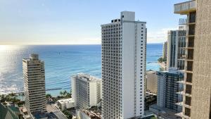 an aerial view of a tall white building next to the ocean at THE MAKAI SUITE at THE WAIKIKI BANYAN in Honolulu