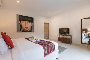 a bedroom with a white bed with a painting on the wall at Villa Briana Seminyak by Bali Villas R Us in Seminyak