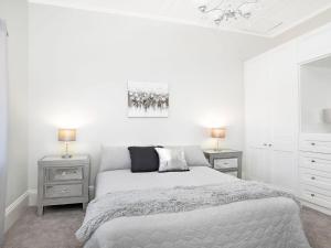 a white bedroom with a bed and two night stands at Advilla in Bowral