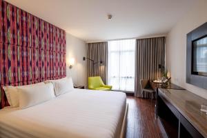 a hotel room with a large bed and a yellow chair at Wynwood Hotel in Manila