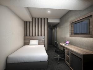 a bedroom with a bed and a desk and a laptop at Smile Hotel Shin-osaka in Osaka