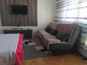 ein Wohnzimmer mit einem Sofa und einem Flachbild-TV in der Unterkunft Apartman Bolero in Bijeljina