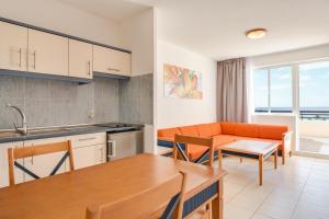 a kitchen and living room with an orange couch at Palm Garden with sea views to the pools and beach in Morro del Jable