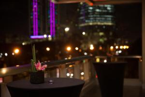 una mesa con una flor en el balcón por la noche en Wynwood Hotel en Manila