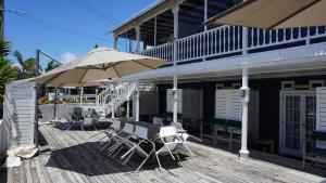 una terraza de madera con mesa y sombrilla en Nana Glads Beachfront Accommodation en Whitianga