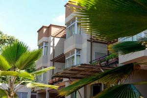 een hoog gebouw met palmbomen ervoor bij Room in Apartment - This Standard Suite offers a brilliant experience with the amenities offered in Kigali