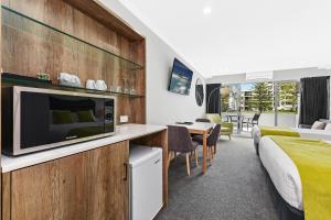 a hotel room with a bed and a tv at Palm Court Motor Inn in Port Macquarie