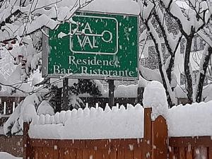 un cartello per un ristorante con una recinzione innevata di Hotel La Val a Valdidentro