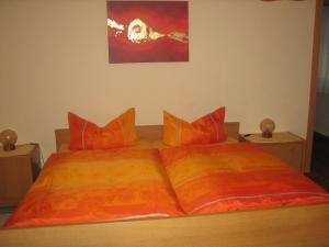 Bett mit orangefarbener Bettdecke und orangefarbenen Kissen in der Unterkunft Haus Gramespacher in Bad Bellingen