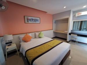 1 dormitorio con 1 cama grande y pared de color naranja en Smile Resort Sriracha, en Si Racha