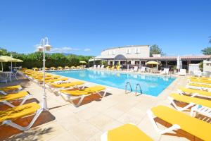 une piscine avec des chaises longues jaunes et un complexe dans l'établissement Hotel Le Lido, à Lucciana