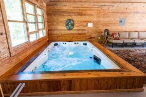 una gran bañera de hidromasaje en una cabaña de madera en PRIVATE Log Cabin with Indoor pool sauna and gym YOU RENT IT ALL NO ONE ELSE, en McAlpin