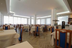 a dining room with tables and chairs and windows at Hotel Toledo in Lido di Jesolo