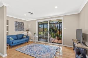 a living room with a blue couch and a tv at Private coastal getaway Corlette in Corlette