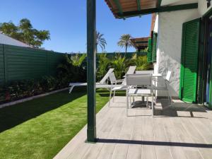 d'une terrasse avec des chaises blanches, une table et de la pelouse. dans l'établissement Prívate bungalow a 200 meters to Yumbo center, à Maspalomas