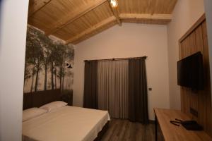 a bedroom with a bed and a flat screen tv at KORU BUTİK OTEL in Artvin