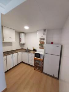 cocina con armarios blancos y nevera blanca en Apartamento a 300 mts de la playa, 25 minutos de Port Aventura y 50 de Barcelona, en Comarruga