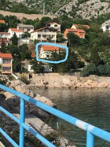 a blue railing next to a body of water with houses at Apartman Nina in Karlobag