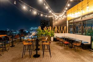 a rooftop patio with tables and chairs at night at Bay Hotel Ho Chi Minh in Ho Chi Minh City