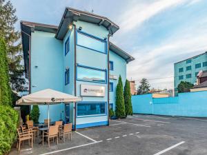 a blue building with chairs and an umbrella in a parking lot at Luxhostel24 Warsaw in Warsaw