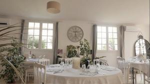 un comedor con mesas blancas y un reloj en la pared en Orangerie du Château Marith - Chambres et Gîtes avec Piscine en Clairac