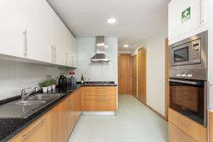 a kitchen with a sink and a stove at Privilege Apartment Wanseta with Rooftop Pool, Village Marina - Olhão in Olhão