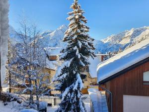 a christmas tree covered in snow next to a building at cellier 7 in Les Deux Alpes