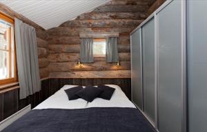 a bedroom with a bed and a wooden wall at Holiday Club Ylläs Apartments and Cottages in Äkäslompolo