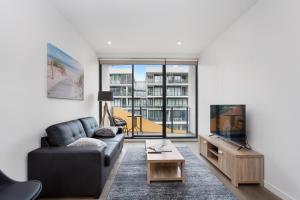 a living room with a couch and a tv at Sandy Hill Apartments by Ready Set Host in Sandringham