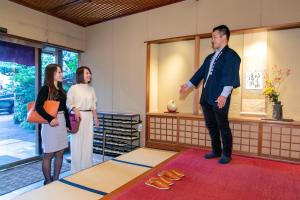 Atami Onsen Yamaki Ryokan في أتامي: رجل وامرأتين واقفين في غرفة