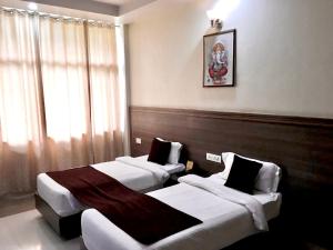 a hotel room with two beds and a chair at Hotel Trihari in Rishīkesh