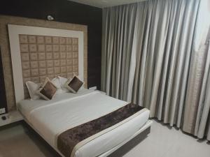 a bedroom with a large bed and a large window at Rudra Shelter International Hotel in Vasai