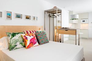 1 dormitorio con cama blanca y almohadas coloridas en Apartamentos y estudios céntricos Conil Home Suite en Conil de la Frontera