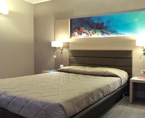 a bedroom with a bed with a painting on the wall at Alma di Alghero Hotel in Alghero