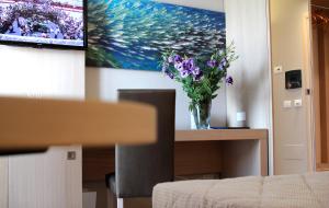 a vase of flowers on a table with a painting at Alma di Alghero Hotel in Alghero