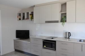 a kitchen with white cabinets and a tv on a counter at Angelwaters in Townsville