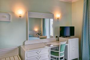 
a bedroom with a dresser, mirror and a television at Grand Hotel Riviera in Sorrento
