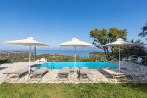 um grupo de cadeiras e guarda-sóis ao lado de uma piscina em Villa Pietra Gialla by Rodostamo Collection em Kassiopi