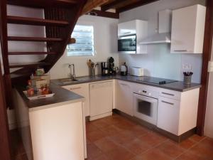 a kitchen with white cabinets and a sink at Villa des Amandiers in Les Anses-dʼArlets