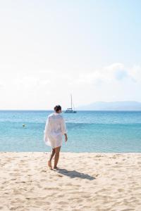 a woman in a white dress walking on the beach at Dionysos Seaside Resort Ios in Mylopotas