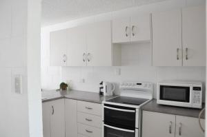 a white kitchen with white cabinets and a microwave at Palm Waters Holiday Villas in Townsville