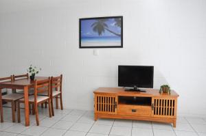 ein Wohnzimmer mit einem Tisch und einem TV auf einem Holzschrank in der Unterkunft Palm Waters Holiday Villas in Townsville