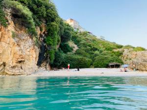 una persona parada en una playa cerca del agua en Hotel Odhisea Qeparo, en Qeparo