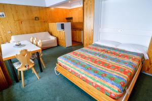 a bedroom with a bed and a table and a chair at Res.Albar&egrave;/Solaria Apt.Solandra in Mezzana