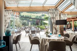 a restaurant with tables and chairs and a large glass window at Quellenhof Luxury Resort Passeier in San Martino