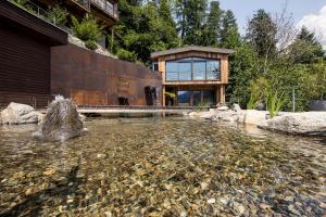 una casa con un laghetto di fronte a un edificio di Quellenhof Luxury Resort Passeier a San Martino