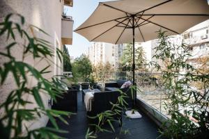 eine Terrasse mit einem Sonnenschirm und Möbeln auf einem Balkon in der Unterkunft Big Tree Apartment & The Nest Apartment - free Parking in Mostar